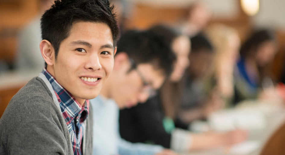 Student in classroom setting smiling at camera