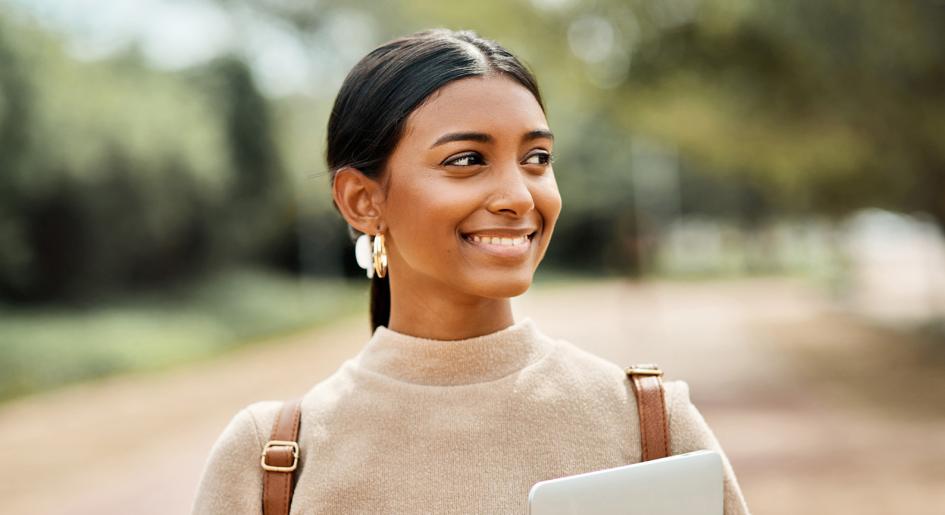 Law student with backpack smiling and holding a tablet