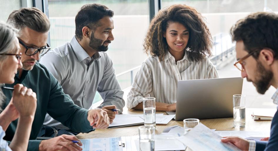 Individuals seated around a conference table looking at data reports