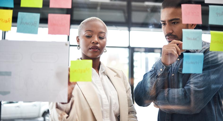 People reviewing post-it notes on conference room glass divider