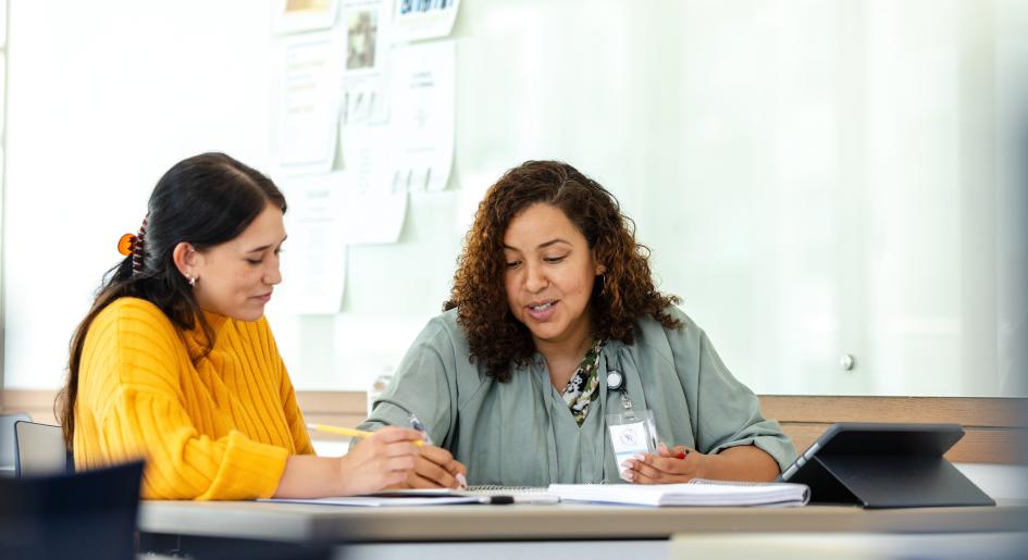 two people at a desk reviewing notes together