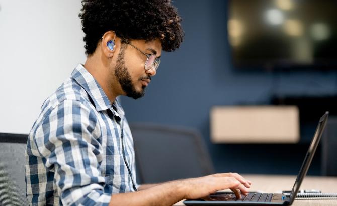 Person with hearing aid at laptop