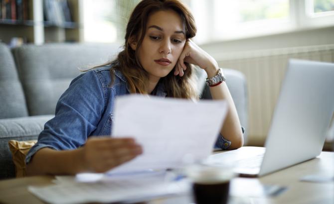 A woman looks at papers with a concerned look on her face