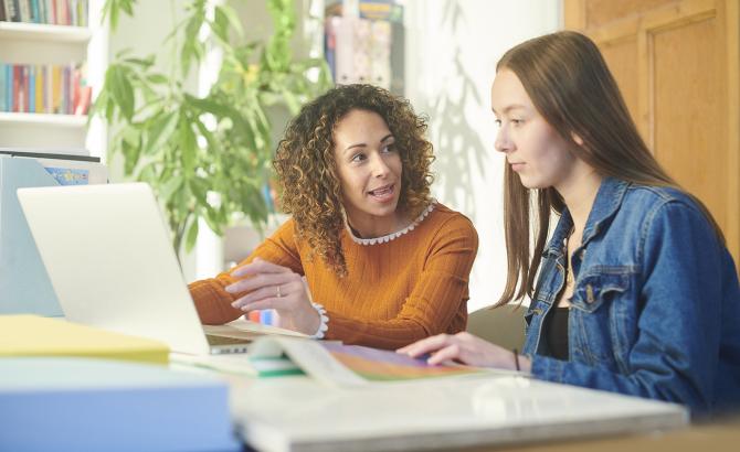 Advisor and student conversing at laptop