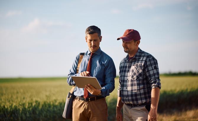 Two men look at a clipboard while standing outside