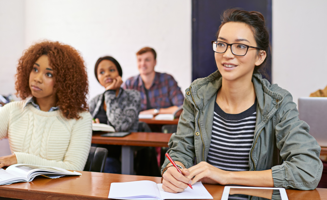 A group of students sit at tables in a classroom
