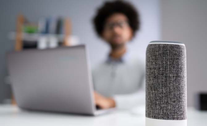 Person at desk with laptop and Amazon Echo device.