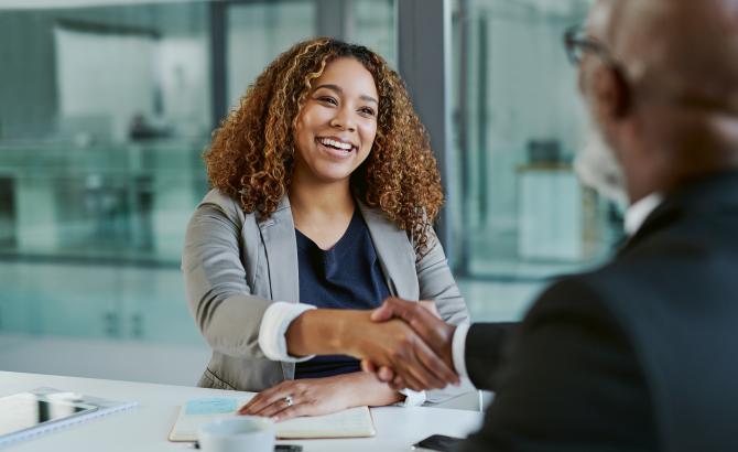 Two people shake hands at a job interview