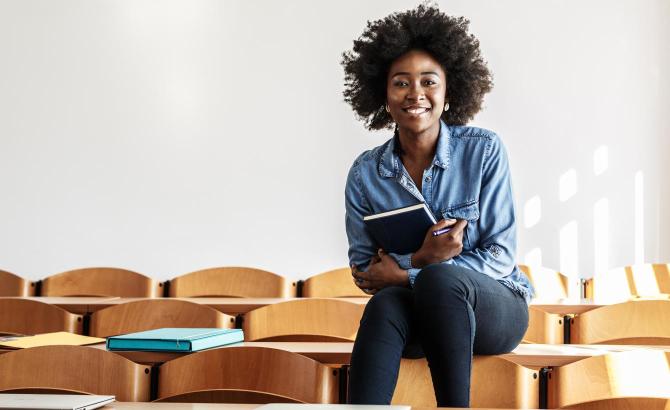 Law student sitting on desk and smiling in classroom