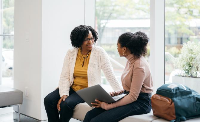 Law student with laptop conversing with professor/mentor.