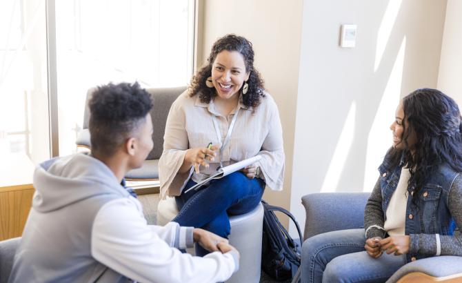 A teacher sits in a circle with two students