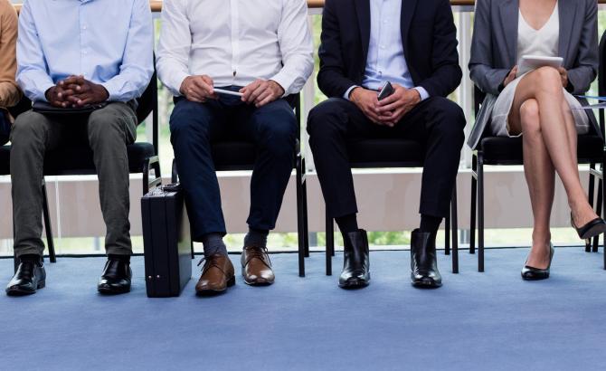 A group of people sit in a line wearing professional clothing