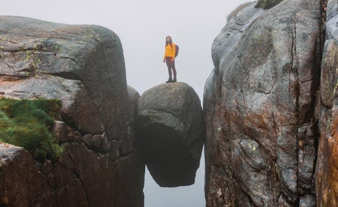 Person standing on rock held between two precipices