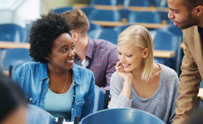 student speaks with a professor in a classroom settings